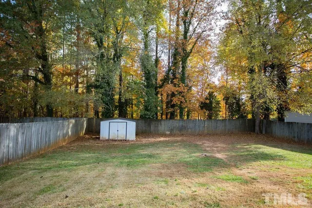 a view of a backyard with large trees and wooden fence