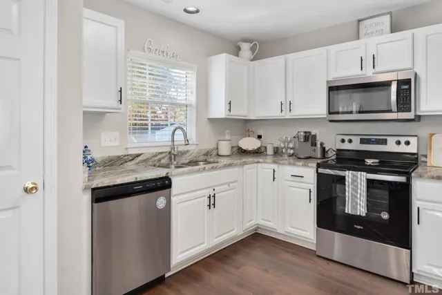 a kitchen with granite countertop white cabinets stainless steel appliances and a sink