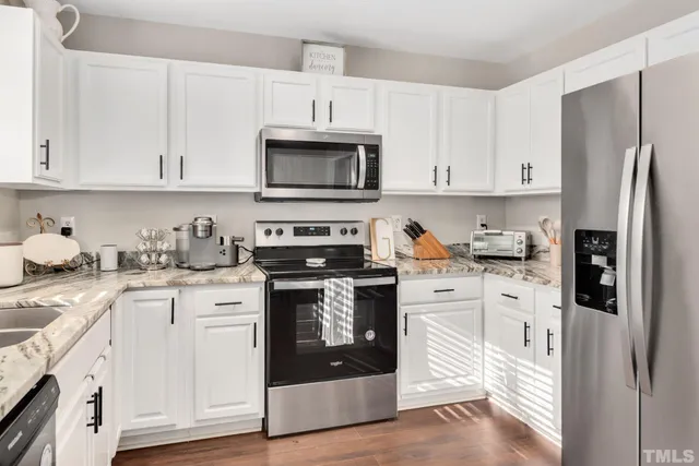 a kitchen with stainless steel appliances granite countertop a refrigerator stove and white cabinets