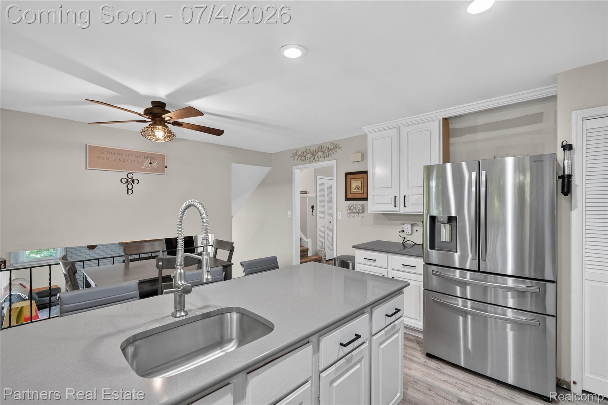 2500 Hubert Road Brighton, MI 48114 - Photo 15 of 53 Kitchen island with a stainless steel sink and gooseneck faucet, white cabinetry, dark countertops, and stainless steel French-door refrigerator