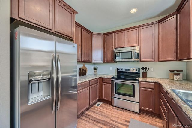 a kitchen with stainless steel appliances granite countertop a refrigerator a stove top oven a sink and dishwasher