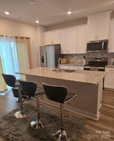 a kitchen with stainless steel appliances granite countertop a table chairs sink refrigerator and microwave