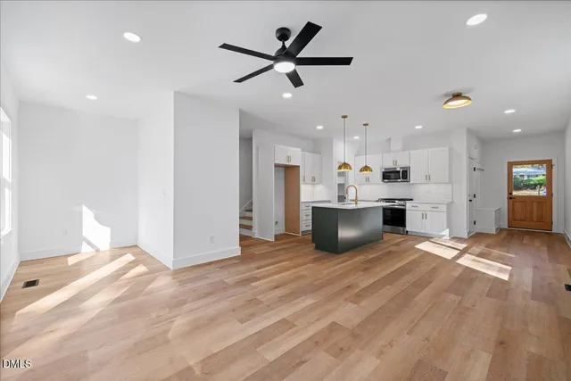 a view of a kitchen with a stove cabinets a ceiling fan and wooden floor