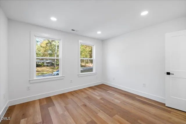 an empty room with wooden floor and windows
