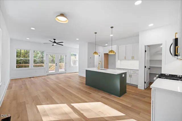 a large kitchen with stainless steel appliances kitchen island a large counter top and a wooden floors