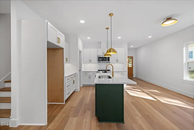 a kitchen with stainless steel appliances granite countertop a sink a stove and a wooden floors