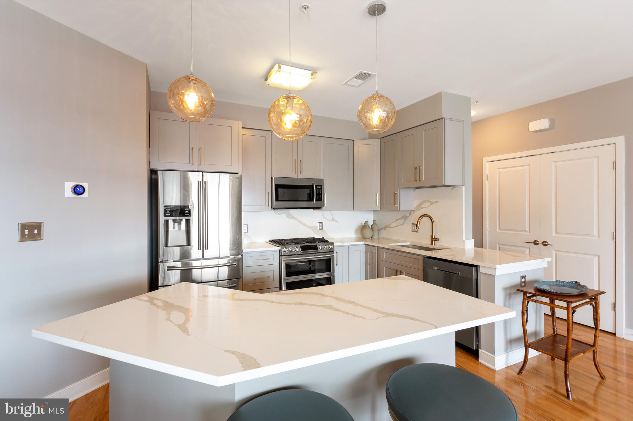 8005 13th Street, Unit 305 Silver Spring, MD 20910 - Photo 20 of 40 a large white kitchen with a table chairs and a refrigerator