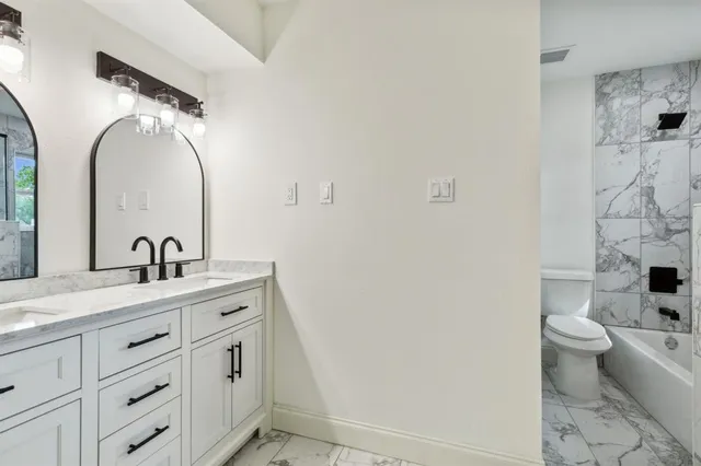 a bathroom with a double vanity sink toilet mirror and bathtub
