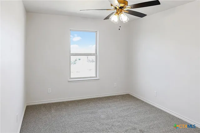 an empty room with a window and a fan