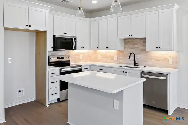a kitchen with cabinets appliances a sink and a counter space