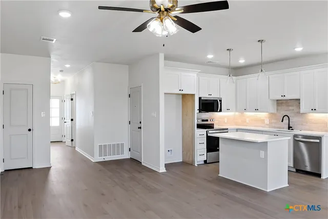 a kitchen with stainless steel appliances a refrigerator and a stove top oven
