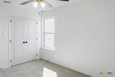 a view of an empty room with a chandelier fan