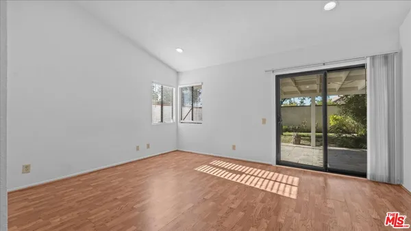 a view of an empty room with wooden floor and windows