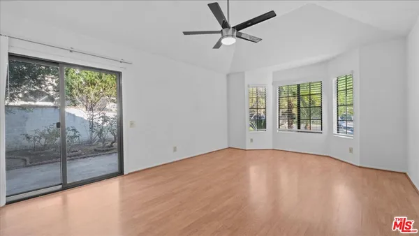 a view of a room with wooden floor a ceiling fan and windows