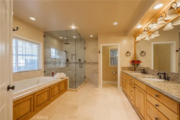a large bathroom with a granite countertop tub a double vanity sink a mirror and a shower