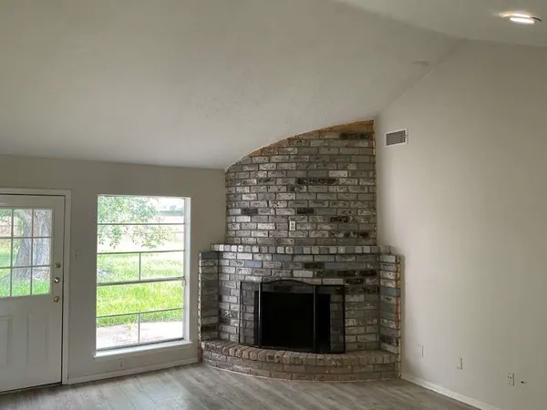 an empty room with windows and fireplace