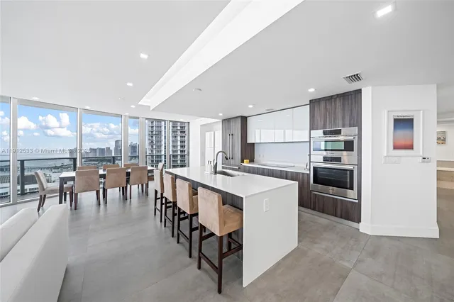 a large white kitchen with a large window and a counter space