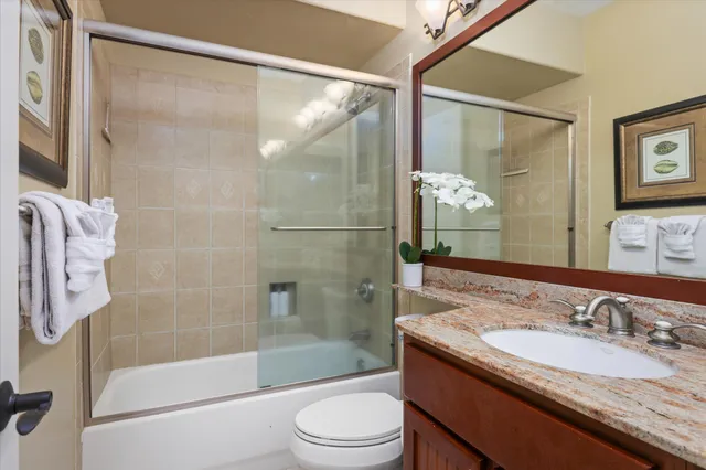 a bathroom with a granite countertop sink toilet and shower