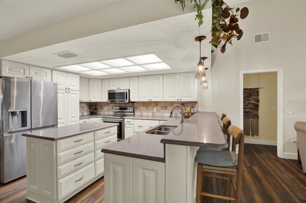 2806 Fairway View Drive Valrico, FL 33596 - Photo 21 of 45 a kitchen with a sink dishwasher a stove a refrigerator cabinets and a dining table with wooden floor