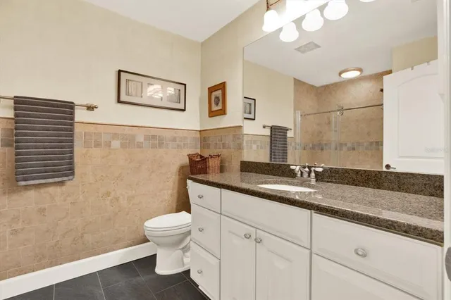 a bathroom with a granite countertop sink a toilet and a mirror