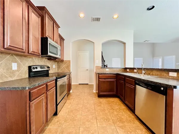 a kitchen with stainless steel appliances granite countertop a stove a sink and a microwave