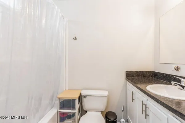 a bathroom with a granite countertop toilet and a sink