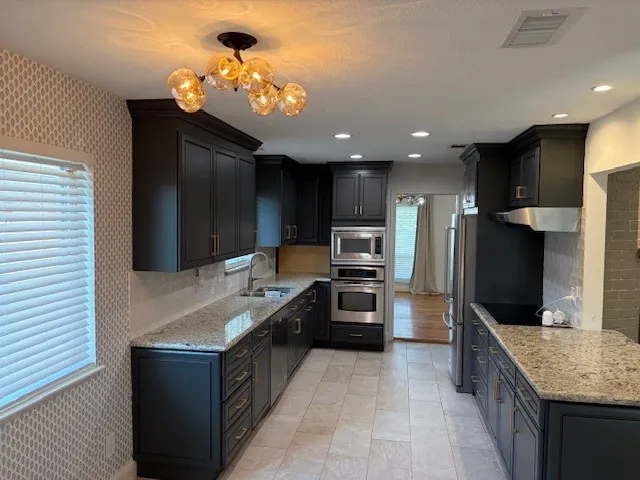 a kitchen with kitchen island granite countertop a sink counter top space appliances and cabinets