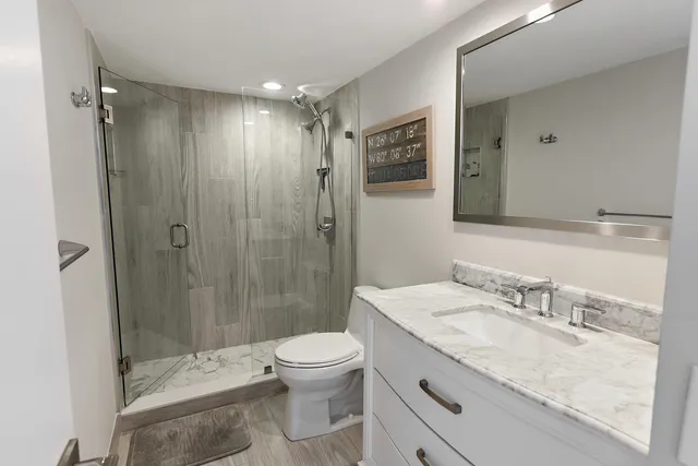 a bathroom with a granite countertop sink toilet and shower