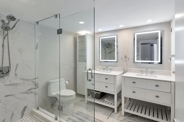 a bathroom with a toilet a sink a mirror and a shower