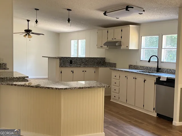 a kitchen with granite countertop cabinets a sink a window and stainless steel appliances
