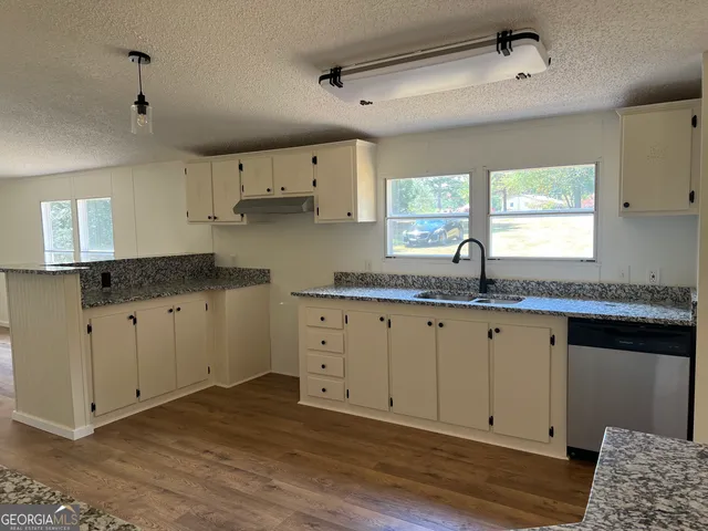 a kitchen with granite countertop white cabinets white appliances a sink and a window
