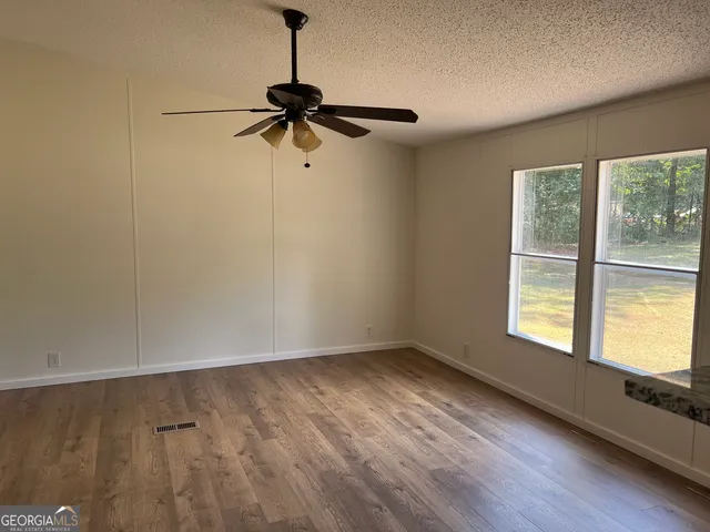 a view of empty room with wooden floor and fan