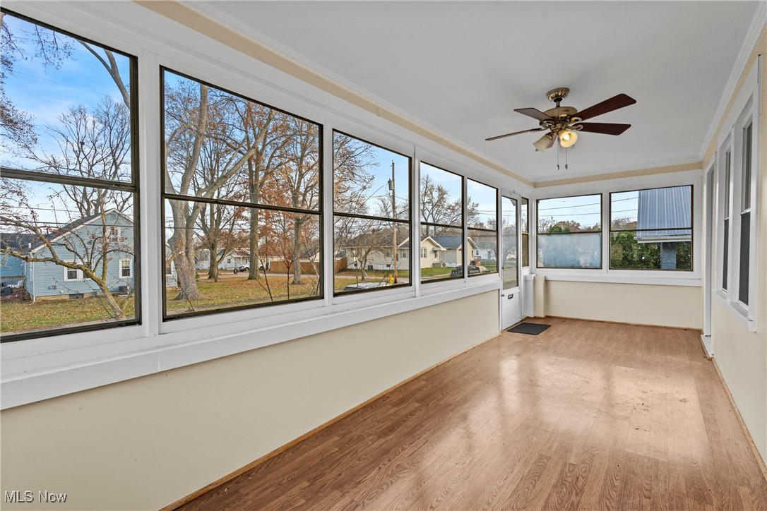 640 Plainfield Road Akron, OH 44312 - Photo 4 of 25 Unfurnished sunroom featuring a ceiling fan, wood finished floors, crown molding, and a residential view