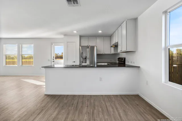 a view of kitchen with stainless steel appliances granite countertop a stove a sink and a refrigerator