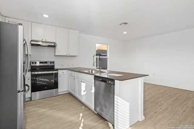 a kitchen with stainless steel appliances granite countertop a stove a refrigerator and a sink