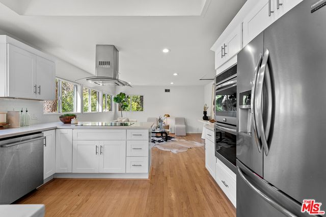 a kitchen with stainless steel appliances a dining table chairs stove and white cabinets