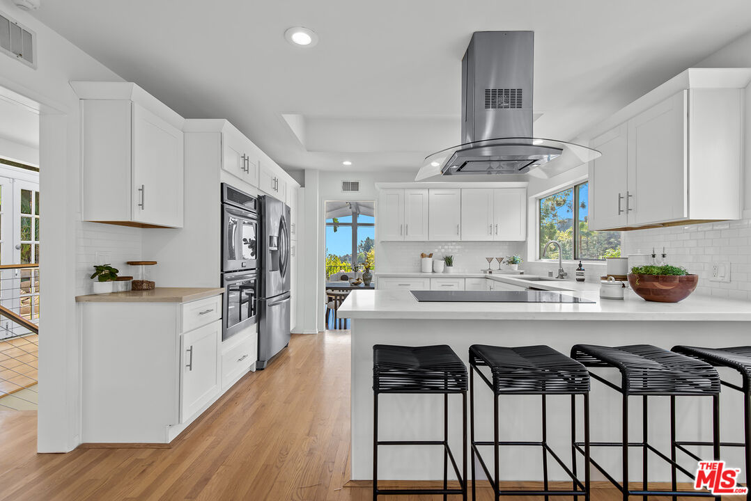 7229 Senalda Road Los Angeles, CA 90068 - Photo 8 of 24 a kitchen with stainless steel appliances a dining table chairs stove and white cabinets