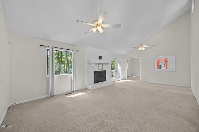 an empty room with windows and fireplace