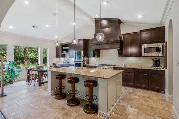 a kitchen with stainless steel appliances granite countertop a sink a stove and a wooden floors