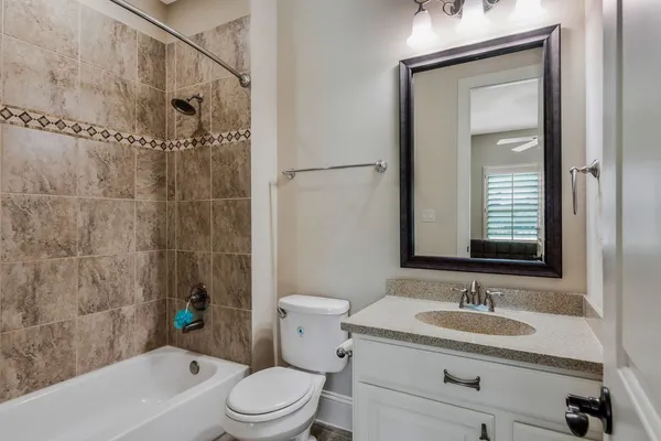 a bathroom with a granite countertop sink toilet a mirror and shower