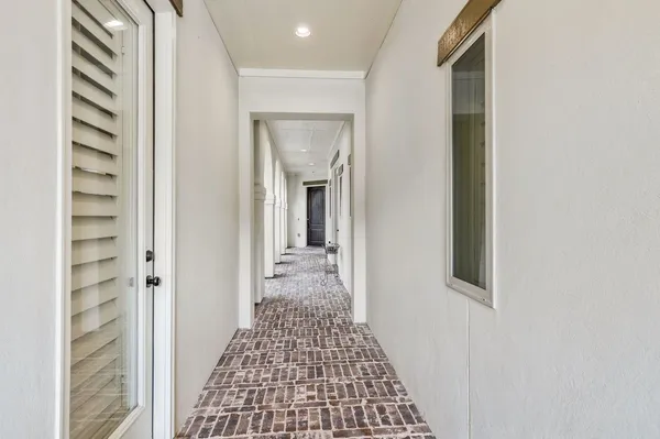 a view of a hallway with wooden floor and a bathroom