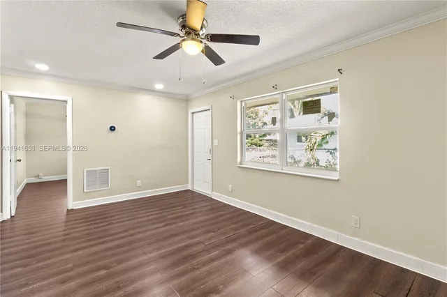 a view of an empty room with wooden floor and a window