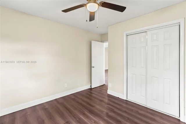 an empty room with wooden floor chandelier fan and windows