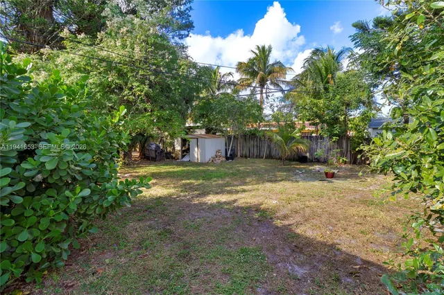 a view of a yard with plants and trees