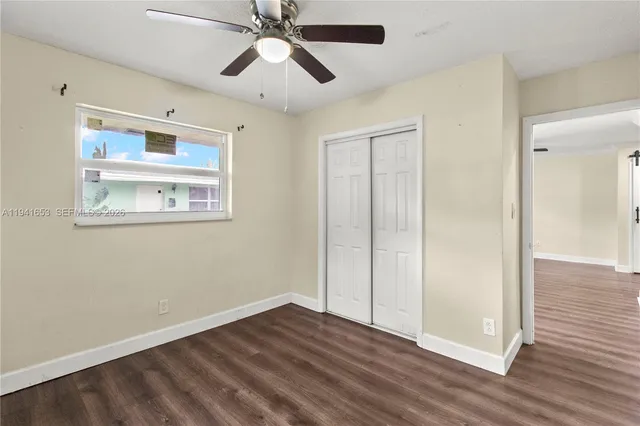 an empty room with wooden floor closet and windows
