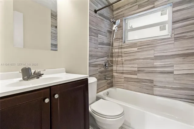 a bathroom with a granite countertop sink toilet a mirror and bathtub