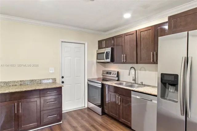 a kitchen with a sink a refrigerator and wooden cabinets