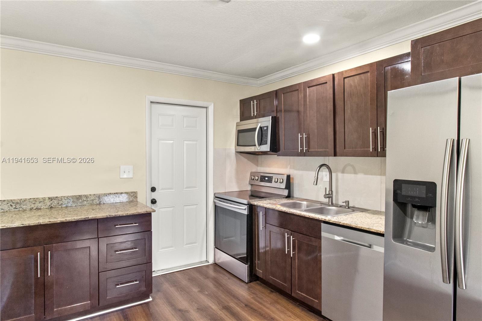 441 Northeast 30th Street, Unit 12 Pompano Beach, FL 33064 - Photo 24 of 33 a kitchen with a sink a refrigerator and wooden cabinets