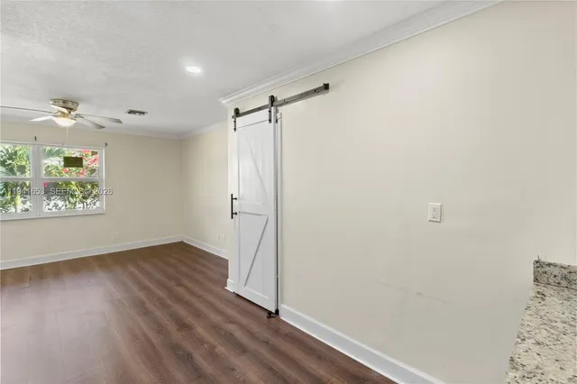 a view of an empty room with a window and wooden floor