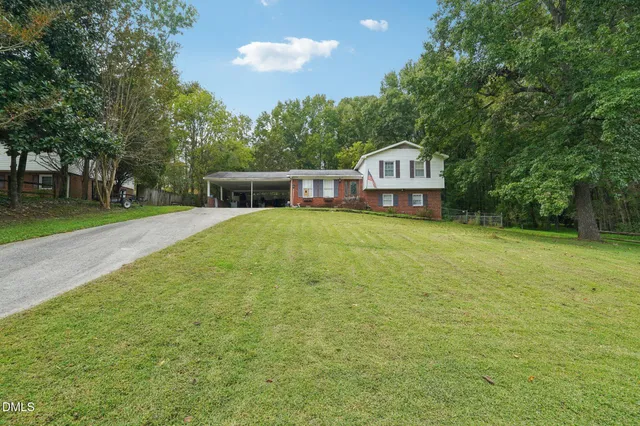 a view of a house with a big yard and large trees